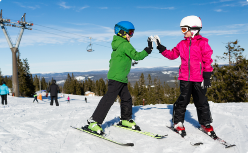 Two young skiiers high-fiving next to a chairlift.