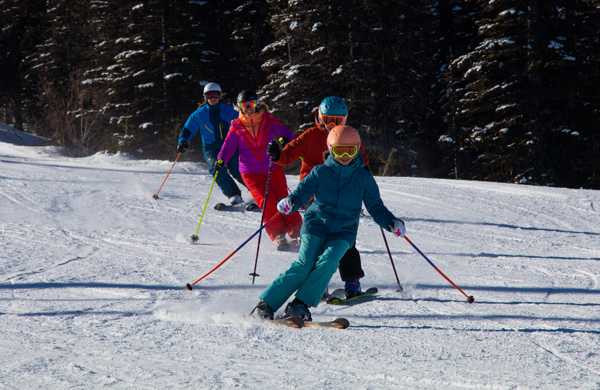 Group of young kids skiing with their parents.